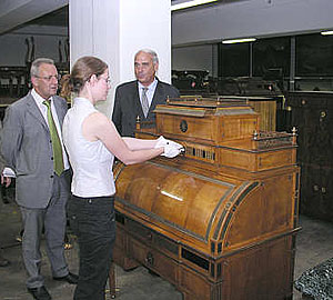 Finanzstaatssekrtetär Gundolf Fleischer und Toto-Lotto-Geschäftsführer Friedhelm Repnik lassen sich einen Zylinderschrank aus dem frühen 19. Jahrhundert zeigen