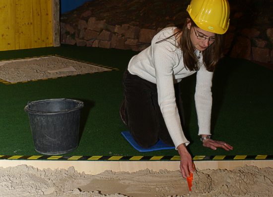 Eine Mitarbeiterin des Museum bei der Demonstration: Schicht um Schicht wird die Erde sorgfältig abgeräumt